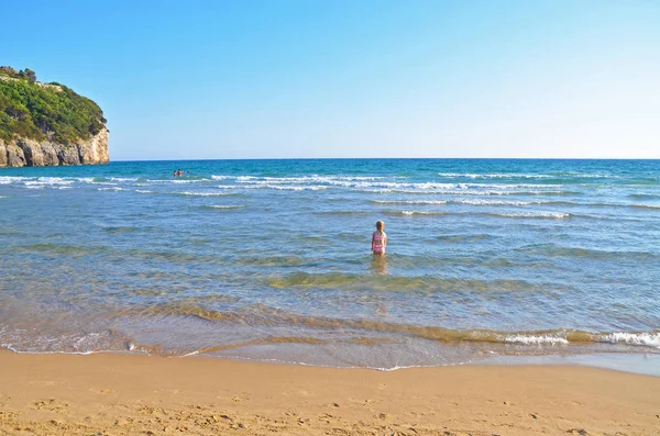 Dívka jde z pláže do zářivě modré moře — Stock fotografie