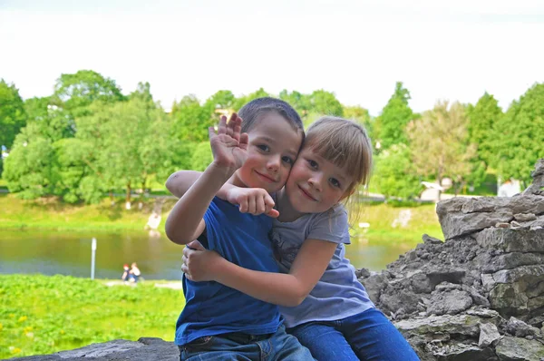 Older sister hugs brother in a clear sunny summer day