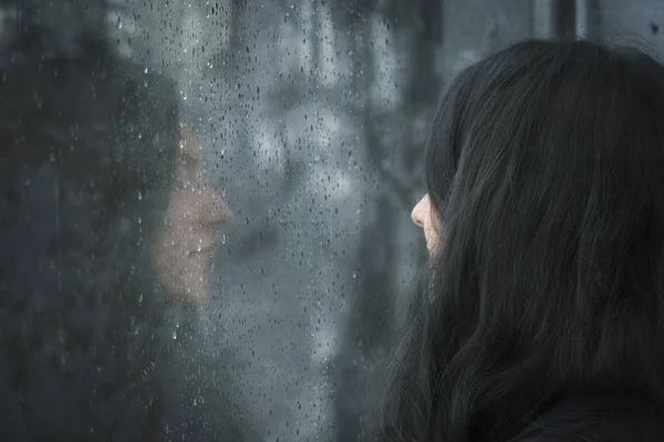 Woman in front of rainy window — Stock Photo, Image