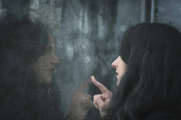 Woman looking on rainy window — Stock Photo, Image