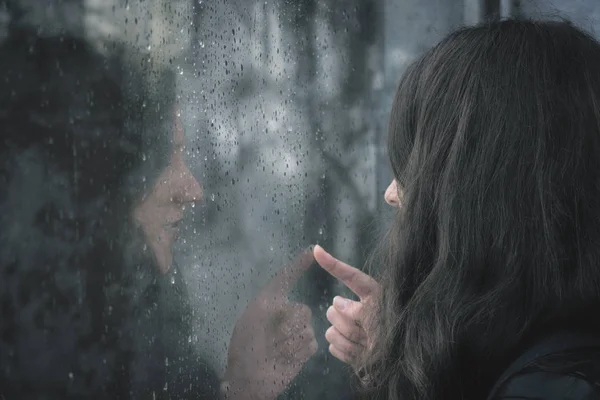 Young woman touching rainy window — Stock Photo, Image