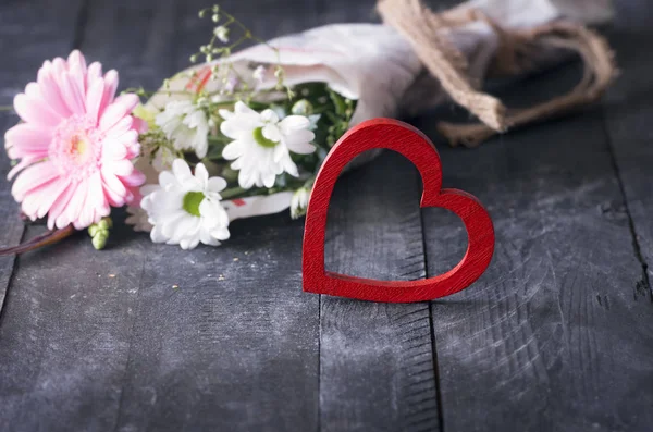 Ljusa röda hjärta och en bukett blommor — Stockfoto