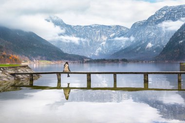 Bir güvertede bir göl üzerinde oturan kız