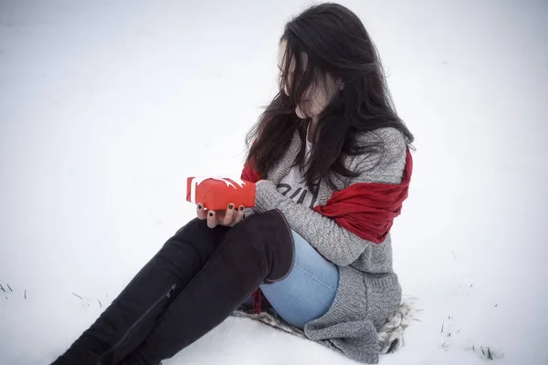 Kobieta trzyma prezent i siedzi na śniegu — Zdjęcie stockowe