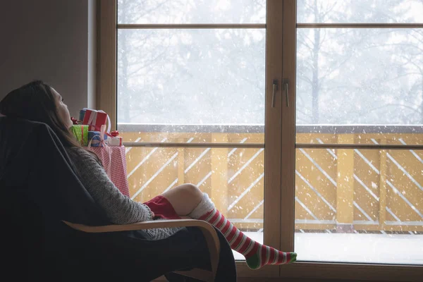 Vrouw in fauteuil voor een besneeuwde raam — Stockfoto