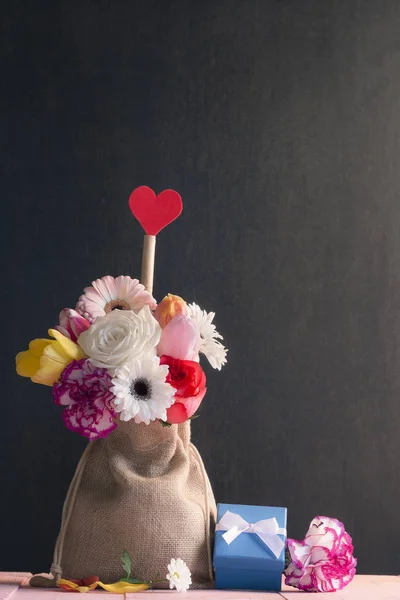 Strauß bunter Blumen und ein blaues Geschenk — Stockfoto