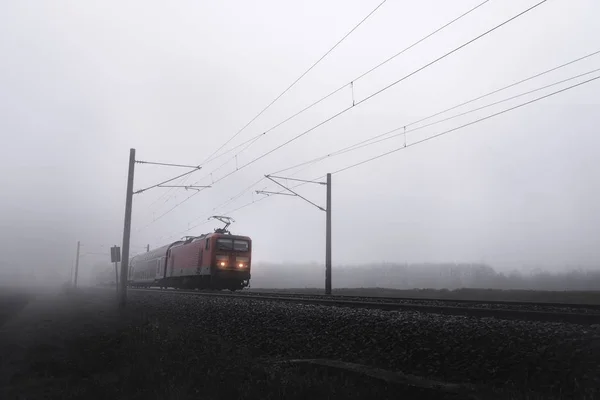 Rote Lokomotive im Nebel bewegt sich auf Bahngleisen — Stockfoto