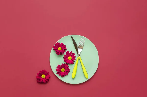 Placa verde con cubiertos y flores rojas. Mesa de cena de primavera — Foto de Stock