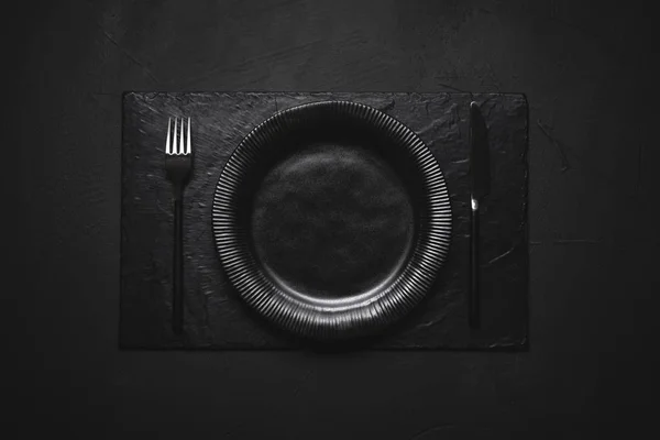 Empty black dish and cutlery on black table. Black table arrange — Stock Photo, Image