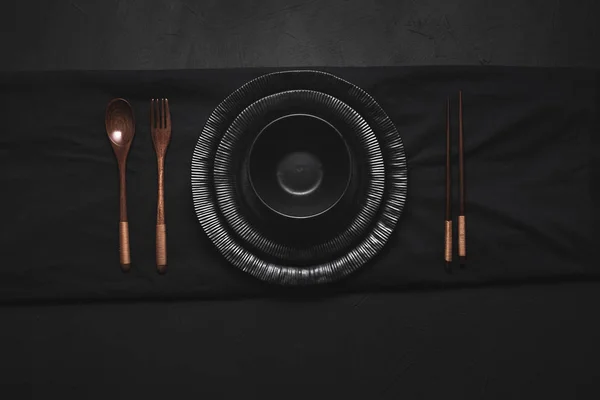 Black dishes with bamboo cutlery and chopsticks. Japanese tablew — Stock Photo, Image