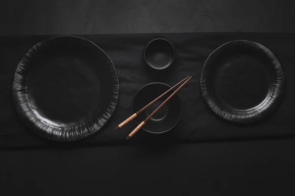 Vajilla negra japonesa y palillos de bambú. Platos vacíos — Foto de Stock
