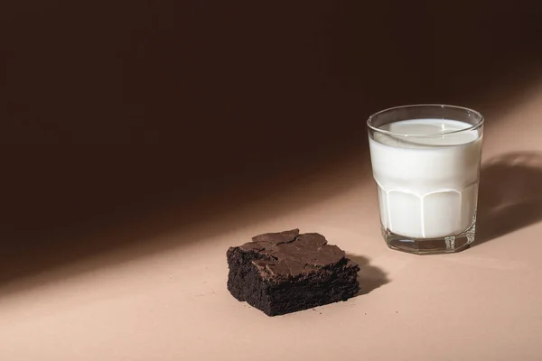 Glass of milk and brownie cookie in sunlight. Sweet breakfast — Stock Photo, Image