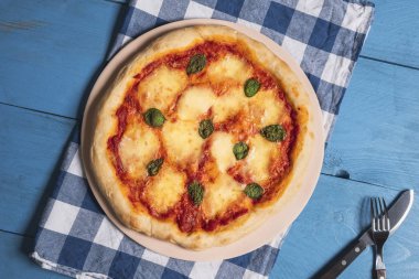 Margherita pizza ve çatal bıçak takımı mavi bir masada. Peynirli pizza. 