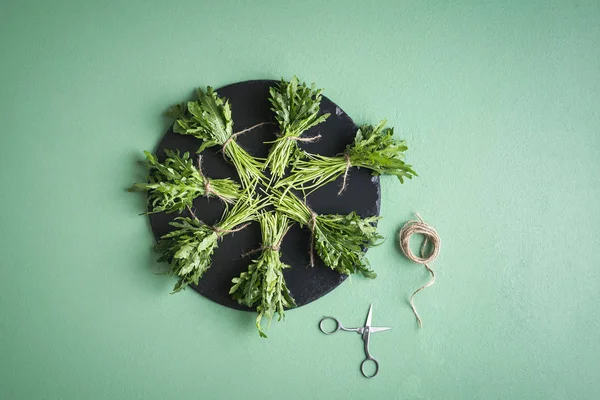 Arugula bundles on platter on green table. Making arugula bundle