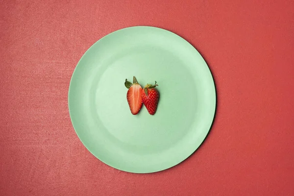 One strawberry cut in half on green plate. Two strawberry halves — Stock Photo, Image