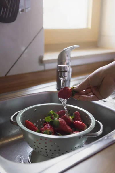Мыть клубнику в кухонной раковине. Спелые клубничные плоды — стоковое фото