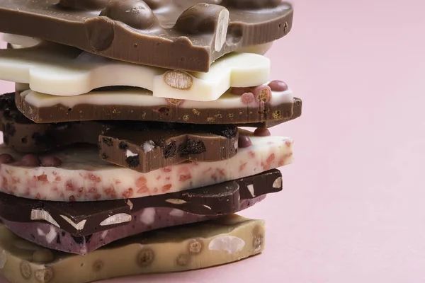 瑞士巧克力在粉红的背景上堆叠在一起 混合不同类型的巧克力 巧克力特写 白巧克力和黑巧克力片 — 图库照片