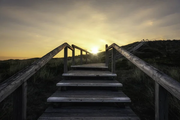 日の出にシルト島の木製の階段 草の多い砂丘の背後に太陽のあるシルト海岸線 登山道砂丘 — ストック写真