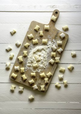 Tahtada pişmemiş gnocchi. Peynirli gnocchi, geleneksel İtalyan makarnası, beyaz masada..