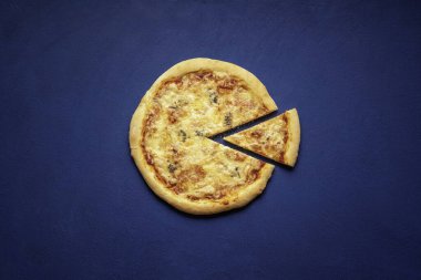 Pizza quattro formaggi evde yapılır. Mavi arka planda dilimlenmiş pizza, manzaranın üstünde. İtalyan pizzası 4 çeşit peynirden yapılır..