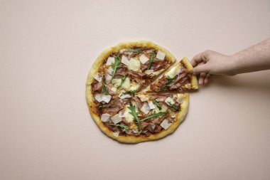 Pembe arka planda roka ve peynirli dilimlenmiş pizza. Pizza dilimli kadın el ele tutuşuyor. İtalyan geleneksel yemekleri.
