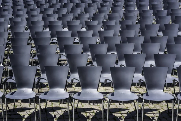 Rows of empty chairs at an open-air theater. Outdoor empty seats background. A pattern of gray seats.