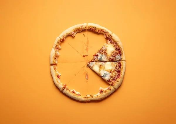 Quattro formaggi pizza slices and crust leftovers on an orange seamless background. Eaten 4 cheese pizza. Two cheese pizza slices. Traditional italian food.