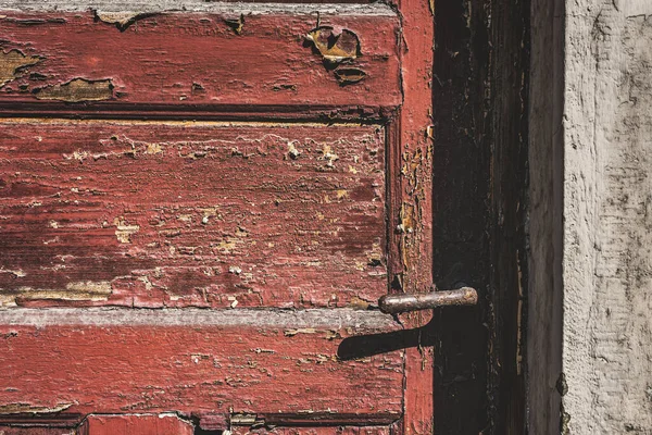 錆びたドアハンドルと割れた赤い塗料で風化した赤いドアのクローズアップ 閉じた扉 — ストック写真