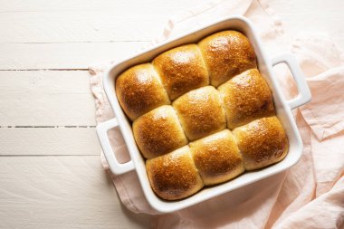 Ekmek çöreklerini beyaz bir seramik tepside, tahta bir masanın üstünde ayır. Ekmek hamuru ve beyaz undan yapılmış ev yapımı ekmek çörekleri. Altın hamurlu ekmek taze pişmiş..