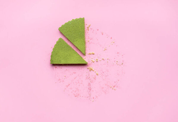 Two slices of matcha cheesecake top view on a pink background. Cheesecake made with matcha green tea powder. Flatlay with the last pieces from a cheesecake on a light pink colored background.