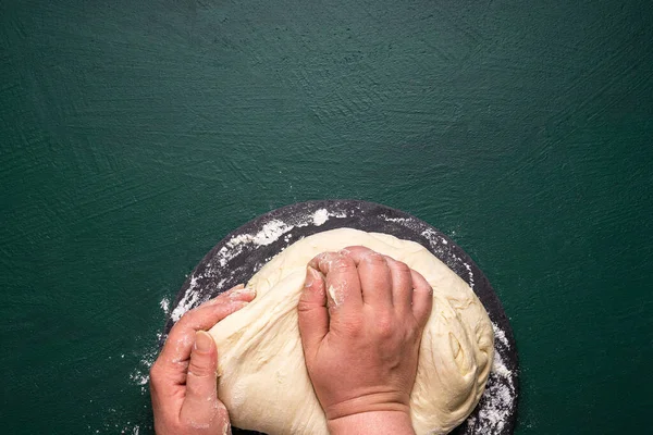 Woman\'s hands making dough for pizza. Fresh homemade pizza dough above view. Unrecognazible woman kneading white flour dough