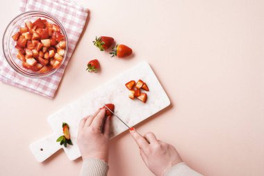 Kadın elleri pembe bir masanın üzerinde çilek dilimliyor. Çilek reçeli yaparken düz uzanıyordu. Evde marmelat yapıyorum..