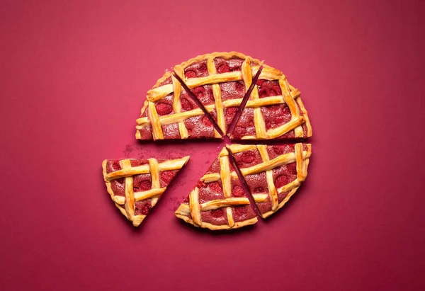 Raspberry pie sliced in equal pieces with lattice crust, on a red background. Top view of raspberry tart with pastry crust. Classic American dessert.