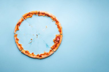 Pizzalı pepperoni artıkları mavi arka planda. Ev yapımı pizza artıkları ve karton üzerinde yağ izleri.