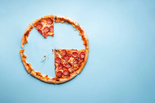 Lezzetli ev yapımı pepperonili pizza ile üst manzara. Mavi arka planda ev yapımı pizza hamuru. Pizza artıkları..