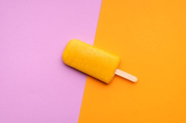 Portakal aromalı buzlu dondurma ve pürüzsüz renkli bir arka plan. Bir meyveli buzlu dondurmanın düz uzanması. Vejetaryen dondurması. Yaz ferahlatıcı tatlı.