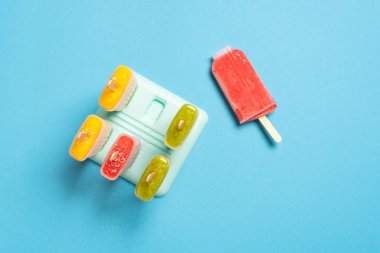 Dondurma kalıpları mavi bir masanın üstünde, üst tarafta. Taze meyveli ev yapımı dondurma. Vejetaryen malzemelerle yapılan yaz tatlısı.