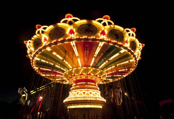 Colorido carrusel oscilación de la cadena en movimiento en el parque de atracciones por la noche . —  Fotos de Stock