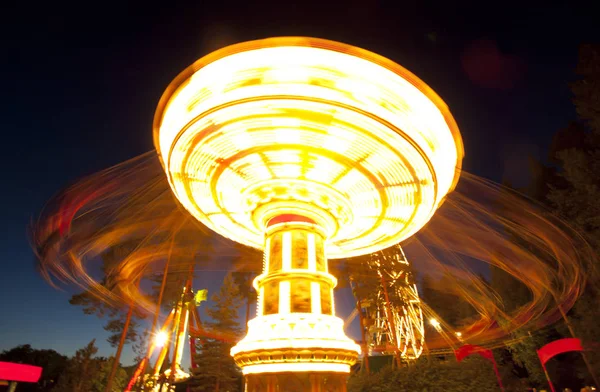 Barevný řetěz houpačka kolotoč v pohybu v zábavním parku v noci. — Stock fotografie