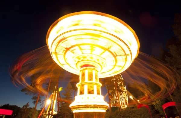 Colorido carrusel oscilación de la cadena en movimiento en el parque de atracciones por la noche . — Foto de Stock