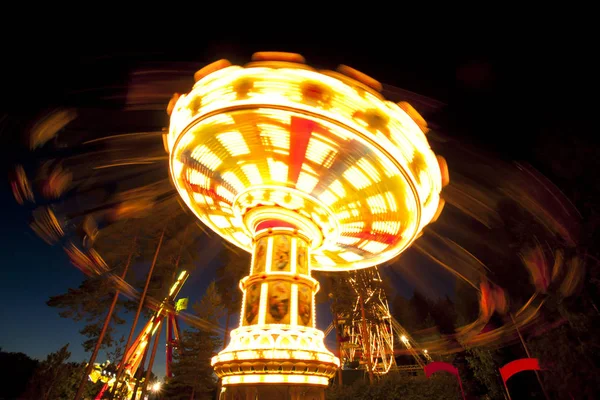 Colorido carrusel oscilación de la cadena en movimiento en el parque de atracciones por la noche . — Foto de Stock