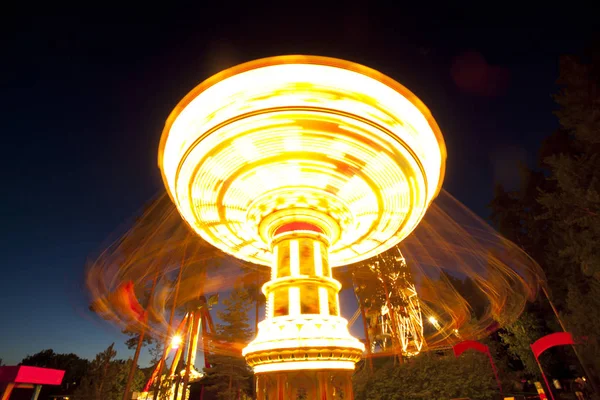 Carrossel de balanço de corrente colorida em movimento no parque de diversões à noite . — Fotografia de Stock