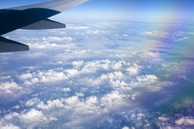 Mavi gökyüzü ve beyaz bulutlu uçak penceresinden bak.