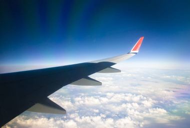 Mavi gökyüzü ve beyaz bulutlu uçak penceresinden bak.