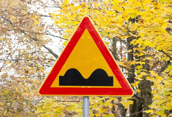 Señal de carretera desigual sobre fondo de hojas de otoño amarillo . —  Fotos de Stock