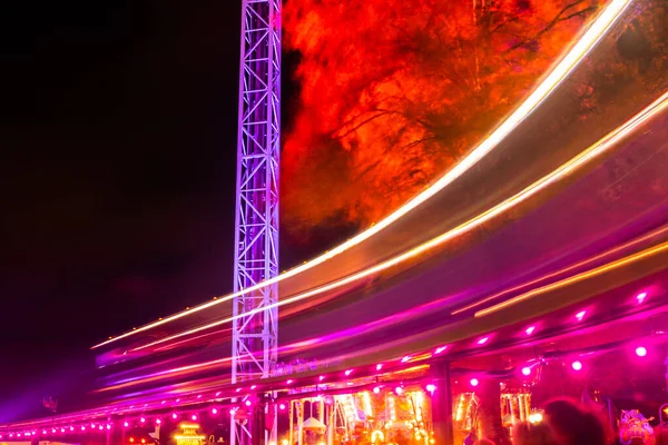 Helsinki, Finland - 19 October 2019: The Carnival of Light event at the Linnanmaki amusement park. Ride train Maisemajuna in motion. Night illumination, long exposure. — ストック写真