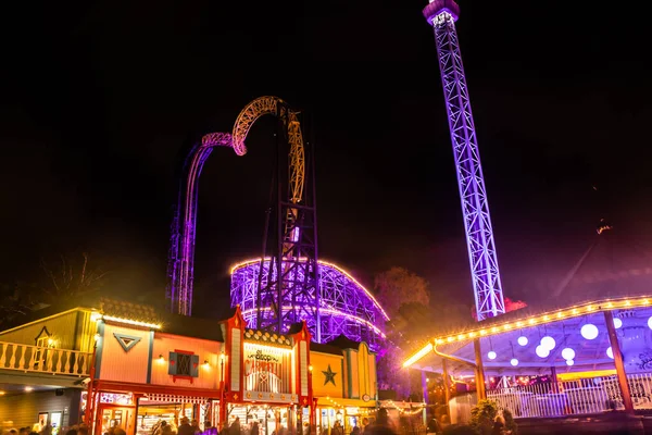 Helsinki, Finland - 19 October 2019: The Carnival of Light event at the Linnanmaki amusement park. Rides Raketti, Ukko and roller coaster Vuoristorata in night illumination. — ストック写真