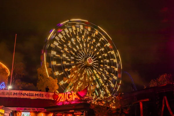 Helsinki, Finland - 19 October 2019: The Carnival of Light event at the Linnanmaki amusement park. Ride Ferris Wheel Rinkeli in motion, night illumination, long exposure. — ストック写真