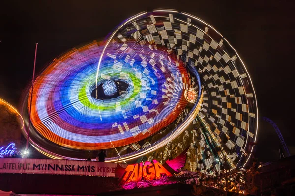 Helsinki, Finlandia - 19 ottobre 2019: Il Carnevale della Luce al parco divertimenti di Linnanmaki. Ride Ruota panoramica Rinkeli e Kehra in movimento, illuminazione notturna, lunga esposizione . — Foto Stock