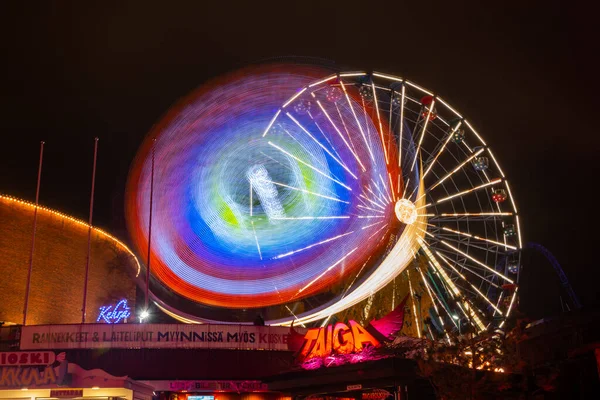 Helsinki, Finlândia - 19 de outubro de 2019: O Carnaval da Luz no parque de diversões Linnanmaki. Passeio Ferris Wheel Rinkeli e Kehra em movimento, iluminação noturna, exposição longa . — Fotografia de Stock